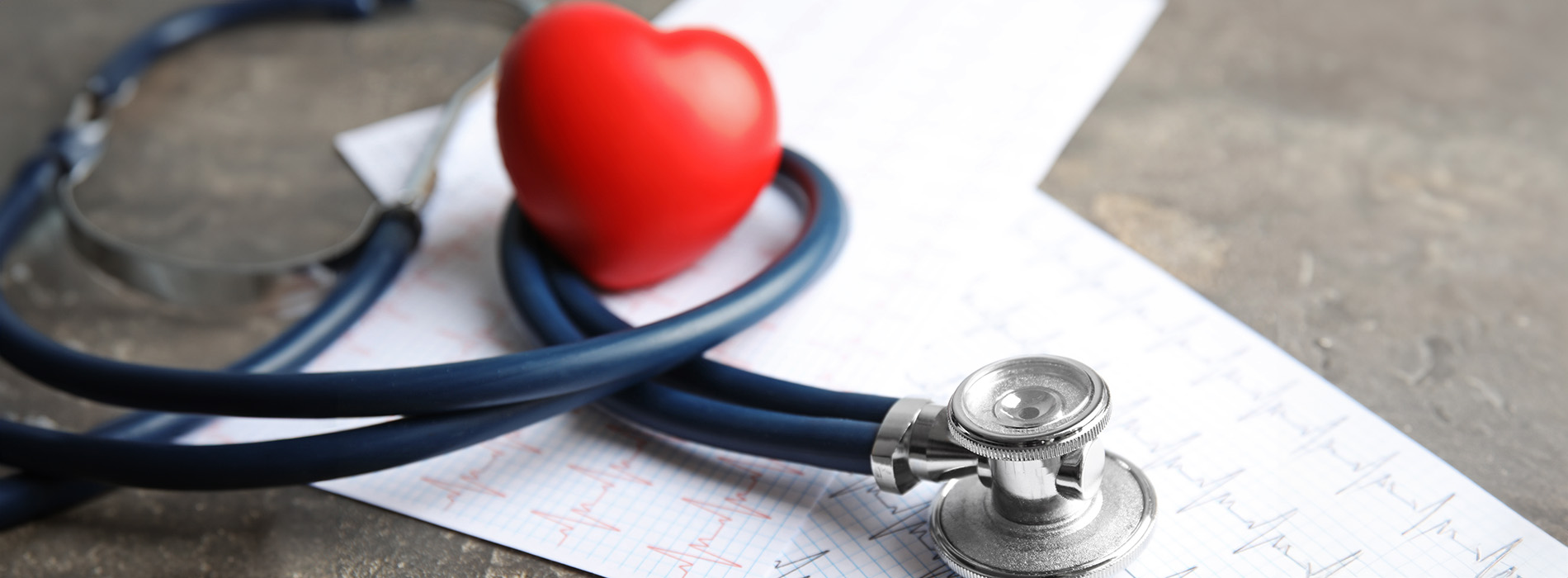 The image features a stethoscope with a heart-shaped pendant placed on top of a medical chart, accompanied by a red pill bottle labeled  heart  with a white cross inside.