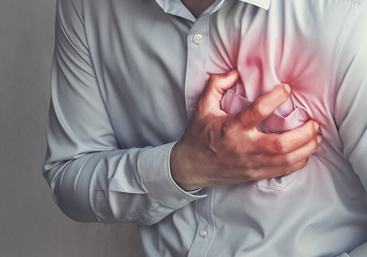 The image shows a person wearing a white shirt with their hand on their chest, indicating a heart condition or pain, with a visible red area representing the heart.