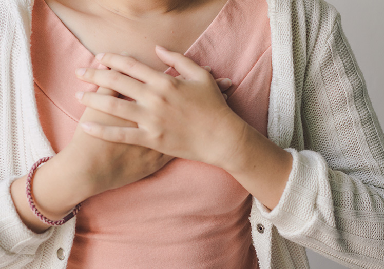 A person s hand on their chest with a concerned expression.
