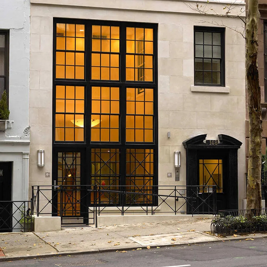 The image shows a building with large windows, featuring an architectural style with a prominent black frame around the windows and a white facade.